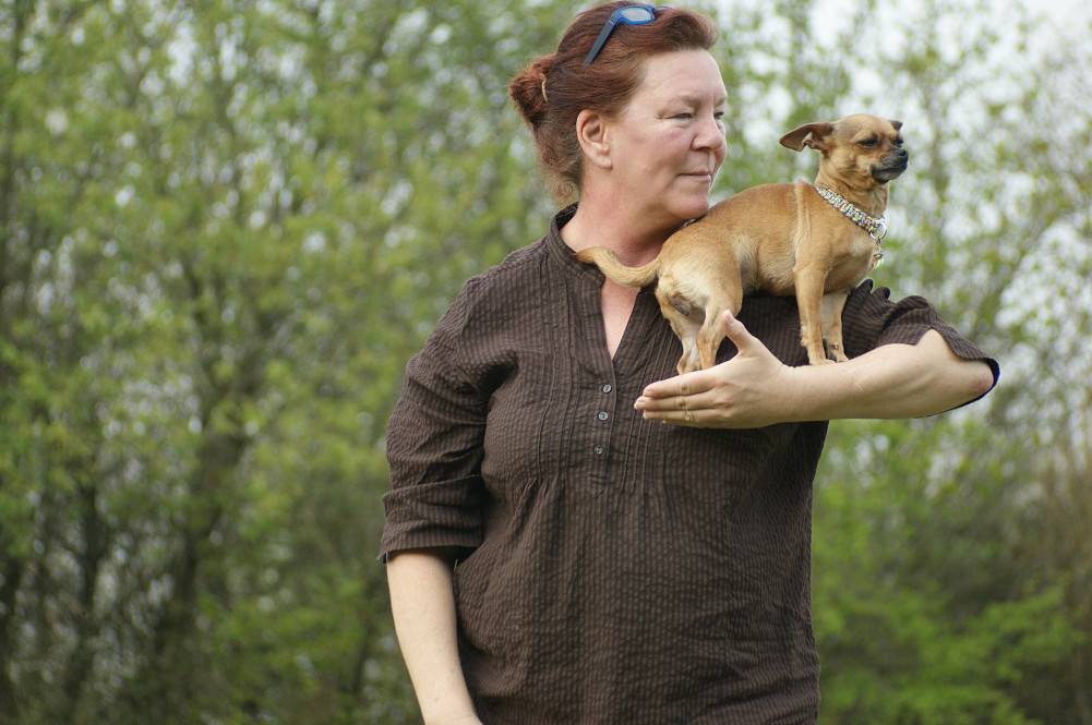 Hund steht auf Unterarm einer Frau